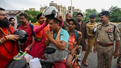 Joint Commissioner Gautam Buddha Nagar, Rajiv Narayan Mishra and DCP Traffic Laxman Singh Yadav and members of Sri Nagambika Dham (Trust) distributed helmets to Kanwariyas at Delhi Noida Chilla Border.&nbsp; (Sunil Ghosh/Hindustan Times)
