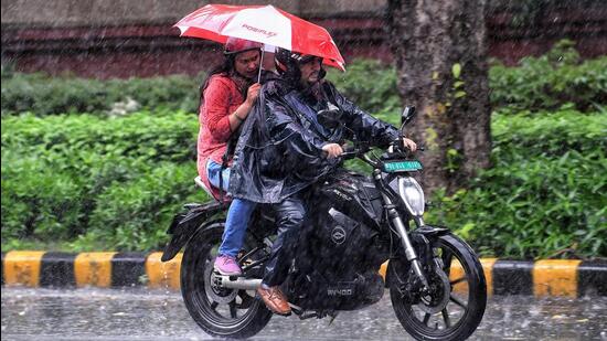 Commuters cover themselves amid heavy rainfall in New Delhi. (ANI Photo)