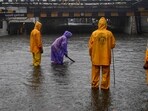 Municipal workers check water level on a flooded road during rain at Andheri subway in Mumbai.