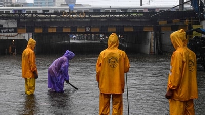 Municipal workers check water level on a flooded road during rain at Andheri subway in Mumbai. (PTI) Municipal workers check water level on a flooded road during rain at Andheri subway in Mumbai. (PTI)