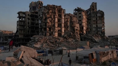 Palestinians walk on an area at a makeshift tent camp located next to buildings destroyed during Israeli air and ground operations, in Gaza City, Friday, July 25, 2025. (AP)