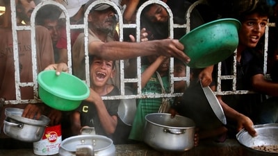 Palestinians shove to receive a hot meal at a charity kitchen in the Mawasi area of Khan Yunis in the southern Gaza Strip. (AFP)