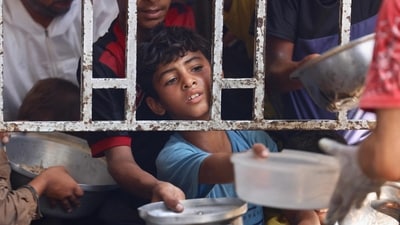 A Palestinian boy seeks a cooked meal at a charity kitchen in the Mawasi area of Khan Yunis in the southern Gaza Strip. (AFP)