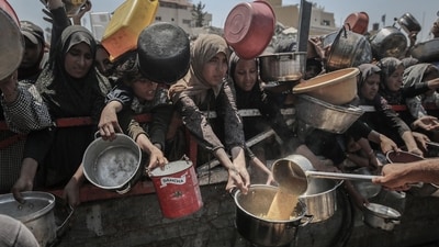 Palestinians hold out pans to receive food from a charity distribution point in Gaza City, Gaza, on Friday, July 25, 2025. (Bloomberg)