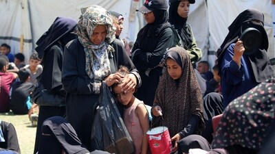 A woman caresses a child's head as Palestinians wait at a food distribution point in the Nuseirat refugee camp in the central Gaza Strip. The World Food Programme said nearly one in three people in Gaza were not eating for days at a stretch and thousands were on the verge of catastrophic hunger. (Eyad Baba/AFP)