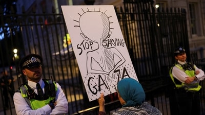 A woman holds a placard in front of police officers outside Downing Street, as people attend a pro-Palestinian protest, featuring the banging of pots and pans to honour the Palestinians shot while queuing for food in Gaza, in London. (REUTERS)
