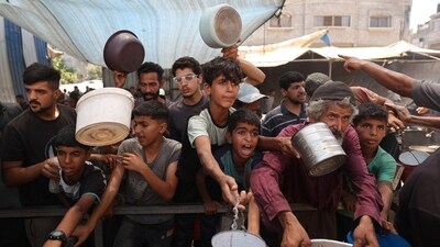 Palestinian children queue for a portion of hot food distributed by a charity kitchen at the Nuseirat refugee camp in the central Gaza Strip (AFP)