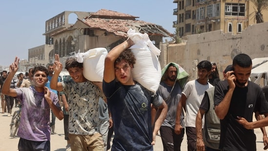 People make their way along al-Rashid street in western Jabalia &nbsp;after receiving humanitarian aid from an aid distribution point in the northern Gaza Strip. The head of Gaza's largest hospital said 21 children have died due to malnutrition and starvation in the Palestinian territory in the past three days, while Israel pressed a devastating assault.(Omar AL-QATTAA/AFP)
