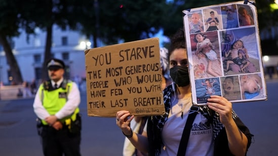 A woman holds placards, as people attend a pro-Palestinian protest outside Downing Street, a demonstration featuring the banging of pots and pans to honour the Palestinians shot while queuing for food in Gaza, in London, Britain, July 25, 2025.&nbsp;(REUTERS/Isabel Infantes)
