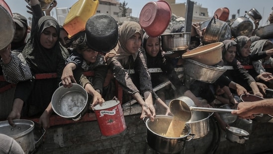 Palestinians hold out pans to receive food from a charity distribution point in Gaza City, Gaza, on Friday, July 25, 2025.(Bloomberg)