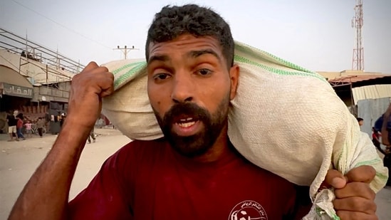 A man walks carrying one of sacks of flour that were taken from a raided truck carry sacks of flour after raiding a truck that was carrying foodstuffs, in Khan Yunis in the southern Gaza Strip.(AFP)