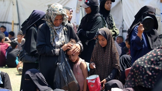 A woman caresses a child's head as Palestinians wait at a food distribution point in the Nuseirat refugee camp in the central Gaza Strip. The World Food Programme said nearly one in three people in Gaza were not eating for days at a stretch and thousands were on the verge of catastrophic hunger.(Eyad Baba/AFP)