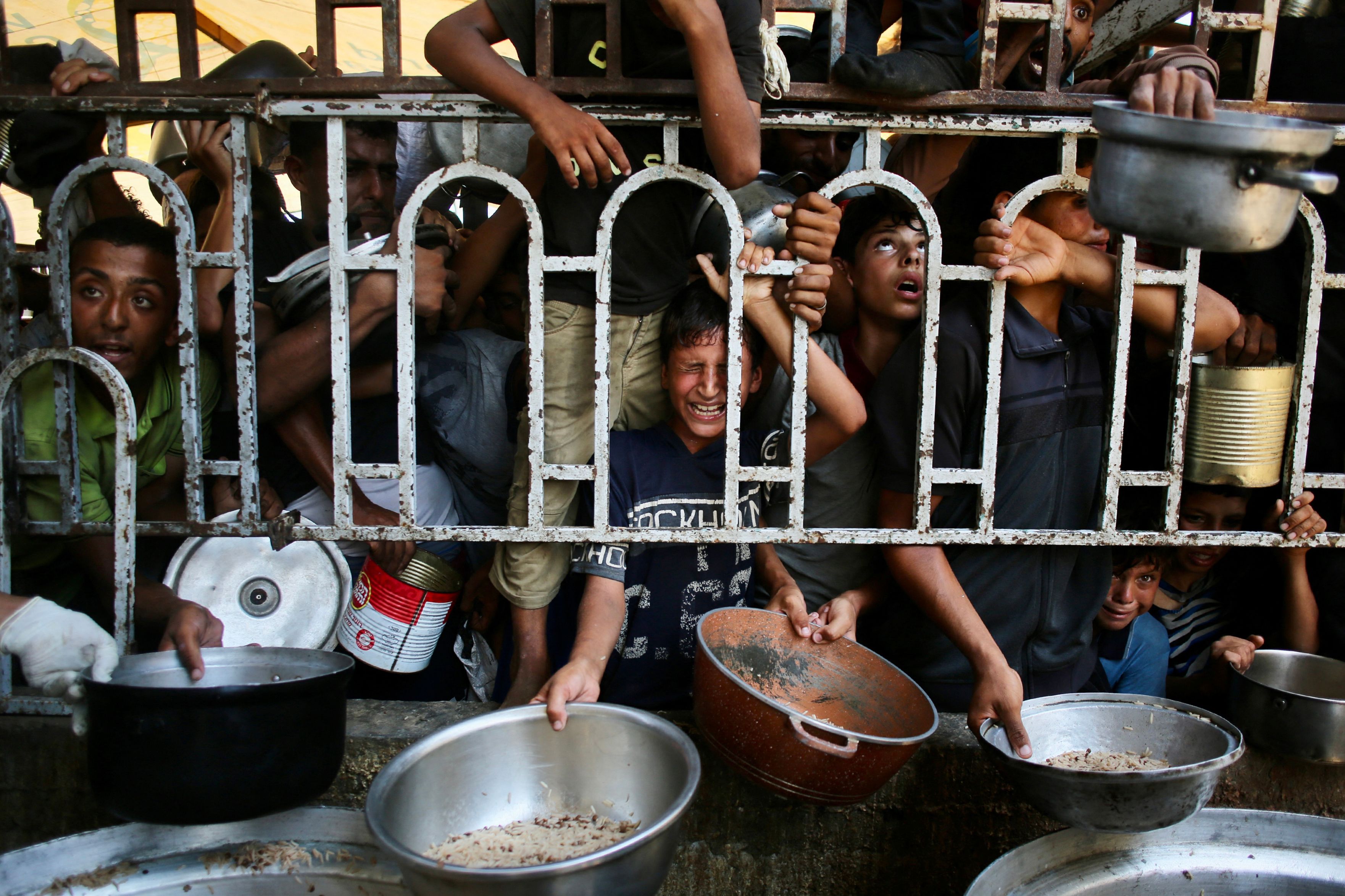 Palestinian children wait for a meal at a charity kitchen in the Mawasi area of Khan Yunis in the southern Gaza Strip. (AFP)