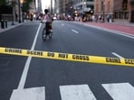 A cyclist is seen behind crime scene tape as police respond to a shooting incident in the Midtown Manhattan neighborhood of New York on July 28, 2025. 