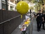 New York City police officers walk past flowers placed outside the midtown office building where a gunman killed four people on July 29, 2025 in New York City.