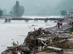 People walk by a damaged bridge after heavy rainfall flooded the area, in Huairou district of Beijing, China July 28, 2025.