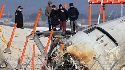 Investigators stand by the mound where the instrument landing system localiser is located, at the scene where a Jeju Air Boeing 737-800 aircraft crashed and burst into flames at Muan International Airport. (AFP) Investigators stand by the mound where the instrument landing system localiser is located, at the scene where a Jeju Air Boeing 737-800 aircraft crashed and burst into flames at Muan International Airport. (AFP)