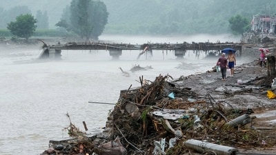 People walk by a damaged bridge after heavy rainfall flooded the area, in Huairou district of Beijing, China July 28, 2025. (via REUTERS)