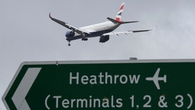 A passenger plane flies over a road direction sign as it makes its landing approach to Heathrow Airport in west London. (REUTERS/File)