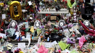 Floral tributes from family and fans left at the Black Sabbath Bridge bench on Broad Street, with pictures of Black Sabbath band members Geezer Butler, Ozzy Osbourne, Tony Iommi, and Bill Ward. (Jack Taylor/REUTERS)