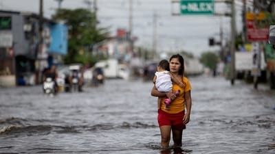A woman carrying a baby wades through a flooded area in Manila North Road following heavy rains brought by Typhoon Co-may in Minalin, Pampanga, Philippines. The storm is now expected to head to Shanghai. (Reuters)