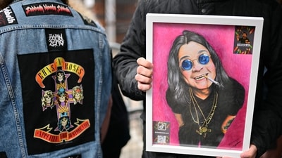 A fan holding an artwork of the late rock icon, hoping to hand it over to his wife, Sharon, when the funeral procession passes through. (Ben STANSALL/AFP) A fan holding an artwork of the late rock icon, hoping to hand it over to his wife, Sharon, when the funeral procession passes through. (Ben STANSALL/AFP)