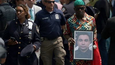 Mourners gathered in the Bronx on July 31 to pay their final respects to NYPD officer Didarul Islam, who was killed in the tragic mass shooting at a Midtown Manhattan office tower on July 28. Among the crowd, a man held a photo of the fallen officer. REUTERS/Jeenah Moon (REUTERS)