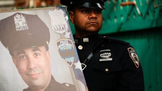A police officer stands with the NYPD officer Didarul Islam's photo frame in hand. REUTERS/Eduardo Munoz(REUTERS)