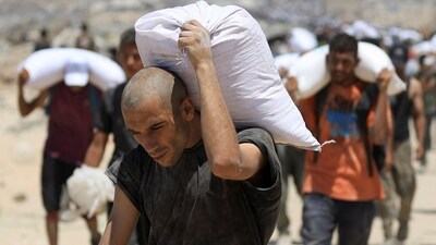 Palestinians in Beit Lahia carry vital aid from Israel, amid rubble and ruins. (Dawoud Abu Alkas/REUTERS)