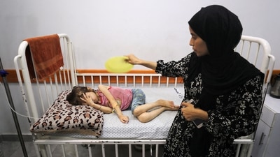 Nasma Ayad fanning her eight-year-old daughter, Jana Ayad in the hospital, hoping to avoid the same fate as the child's sister, who died last month. (Mahmoud Issa/REUTERS)