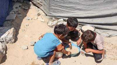Palestinian children share a bowl of soup, amidst growing food scarcity. Gaza’s health authorities say hunger-related deaths are rising, with 156 reported so far, including 90 children, most of whom died in the past few weeks. (Omar Al-Qattaa/AFP)