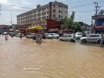 Commuters wade through a waterlogged road after heavy rainfall in Himachal's Una district on Saturday. (PTI)