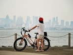 A person stands with a bicycle as smoky haze from wildfires, with a poor air quality rating, covers the skyline of Montreal, Quebec, Canada August 3