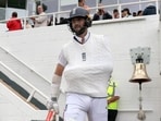 Chris Woakes, with his arm in a sling, tucked under the jumper, walks out to bat