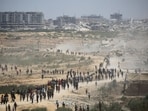 Palestinians rush to the scene as air pallets, carrying humanitarian aid, parachute down after being dropped from a military plane over Nuseirat in the central Gaza Strip during an airdrop mission above the Israel-besieged Palestinian territory on August 5, 2025.