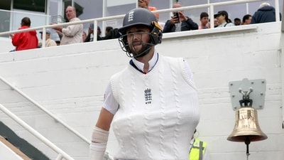 Chris Woakes, with his arm in a sling, tucked under the jumper, walks out to bat (Reuters)