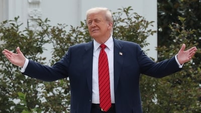 President Donald Trump gestures to reporters during his walk on the White House roof (REUTERS)
