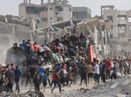People rush towards an truck carrying humanitarian aid as it drives along al-Rashid street in western Jabalia 