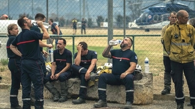 Firefighters drink water and rest at a field command post set up in Saint-Laurent-de-la-Cabrerisse, southern France, where a wildfire has scorched a vast area. (AFP) Firefighters drink water and rest at a field command post set up in Saint-Laurent-de-la-Cabrerisse, southern France, where a wildfire has scorched a vast area. (AFP)