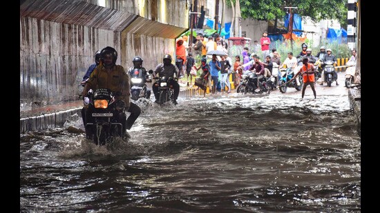 Commuters move through a waterlogged road at George Town area after heavy rainfall, in Prayagraj, on Friday. (PTI)