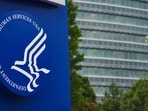 A sign sits as the Center of Disease Control and Prevention (CDC) is pockmarked by bullet holes in the background