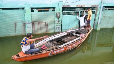 A man rides a boat with others in an area inundated with the swollen Ganga river water, amid monsoon season, in Varanasi, Uttar Pradesh, Saturday, Aug. 9, 2025. (PTI) A man rides a boat with others in an area inundated with the swollen Ganga river water, amid monsoon season, in Varanasi, Uttar Pradesh, Saturday, Aug. 9, 2025. (PTI)