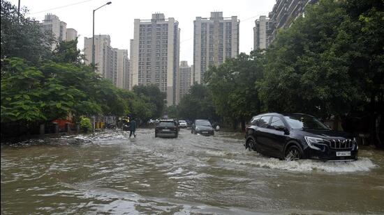 Commuters brave through a flooded stretch in Vaibhav Khand, Ghaziabad on Saturday. (Sakib Ali/HT Photo)