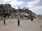 Palestinians walk along a street near war-damaged buildings along the shore in Gaza City.