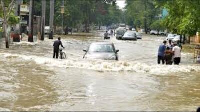Commuters wade through a waterlogged road in an area in Prayagraj. (File Photo)