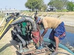 An Indian farmer works on a diesel pump placed to draw sewage treated water from the Fatehwadi canal at Lekhambha village, some 40 kms. from Ahmedabad on March 17, 2018. Indian farmers are using sewage treated water to save their winter crops after Gujarat's government has stopped water supply for irrigation purposes as the remaining water stock is reserved solely for drinking purposes. / AFP PHOTO / SAM PANTHAKY (AFP)