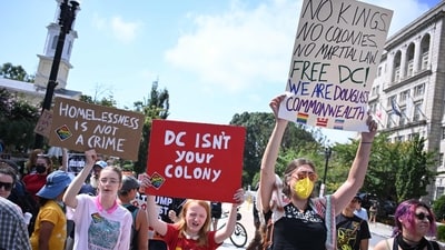 Protestors hold boards during a rally in the capital amid Trump's conference. One of the signboards read, “Homeless is not crime,” while another read, “DC isn't your colony.” (Photo by Mandel NGAN / AFP) (AFP) Protestors hold boards during a rally in the capital amid Trump's conference. One of the signboards read, “Homeless is not crime,” while another read, “DC isn't your colony.” (Photo by Mandel NGAN / AFP) (AFP)