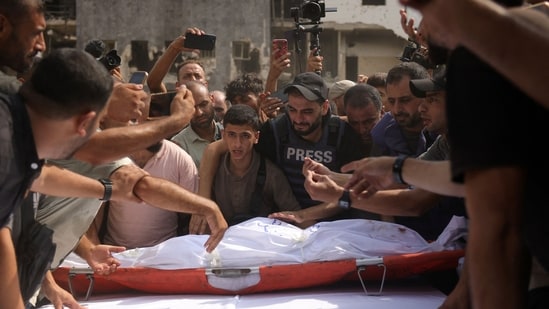 Mourners place the body of Al Jazeera correspondent Anas al-Sharif, who was killed alongside other journalists in an overnight Israeli strike on their tent in Gaza City, on a table ahead of a funeral procession in Gaza City on August 11, 2025.(Bashar Taleb/AFP)