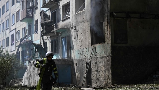 An Ukrainian firefighter carries a water pump to extinguish fire in a residential building at the site of a Russian drone strike in the town of Bilozerske, Donetsk region (AFP/Representational)
