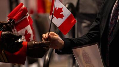 A new Canadian citizen takes a flag during a citizenship ceremony at Canada Place on Canada Day in Vancouver, British Columbia, Canada, on Tuesday. (Bloomberg) A new Canadian citizen takes a flag during a citizenship ceremony at Canada Place on Canada Day in Vancouver, British Columbia, Canada, on Tuesday. (Bloomberg)